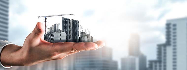 A hand holding a city scape being built